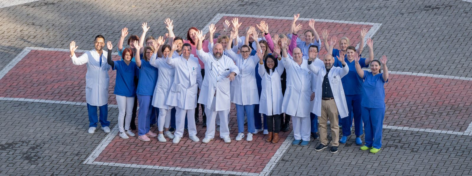 Ein Gruppenfoto der Klinik für Allgemeinchirurgie auf dem Hubschrauberlandeplatz Slider_ACHI_4.jpg
