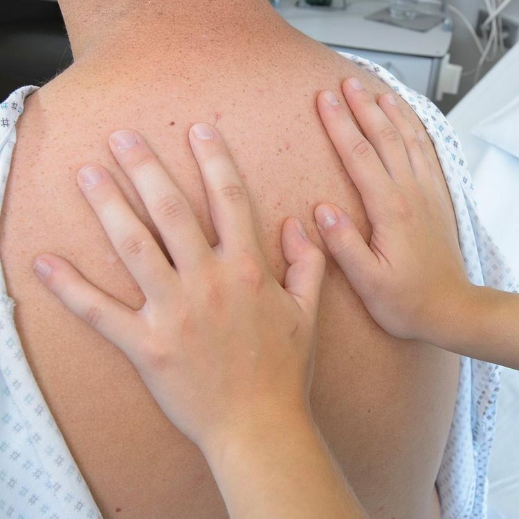 Patient im Krankenhaus - Pflegekraft legt Hände auf den Rücken