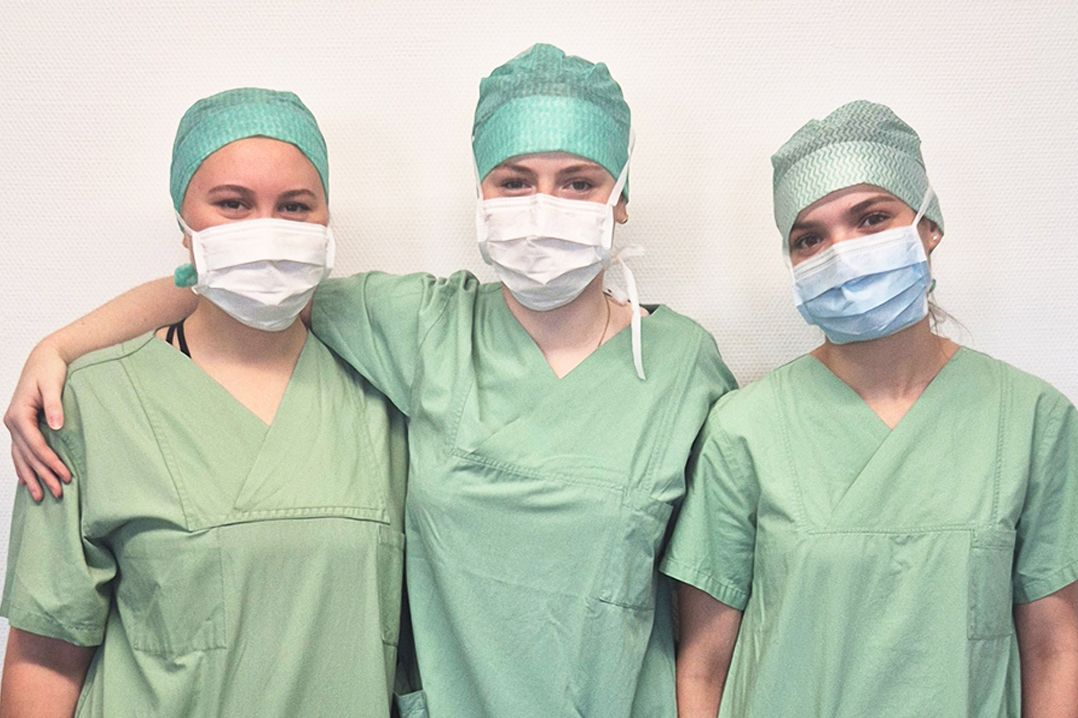 Drei FSJ`lerinnen in grüner Funktionskleidung mit Haube und Mundschutz