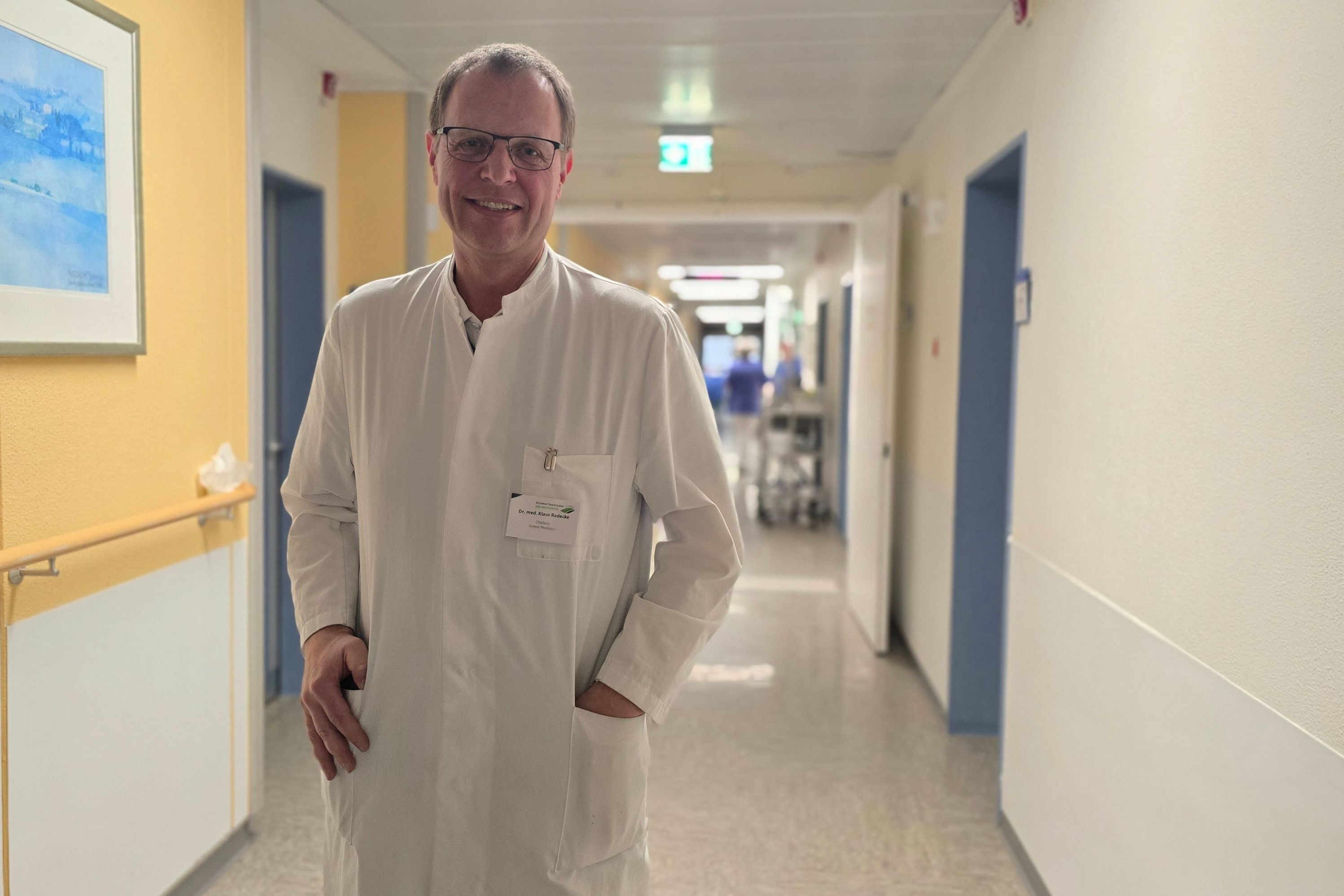 Ein Chefarzt steht in einem Krankenhausflur.