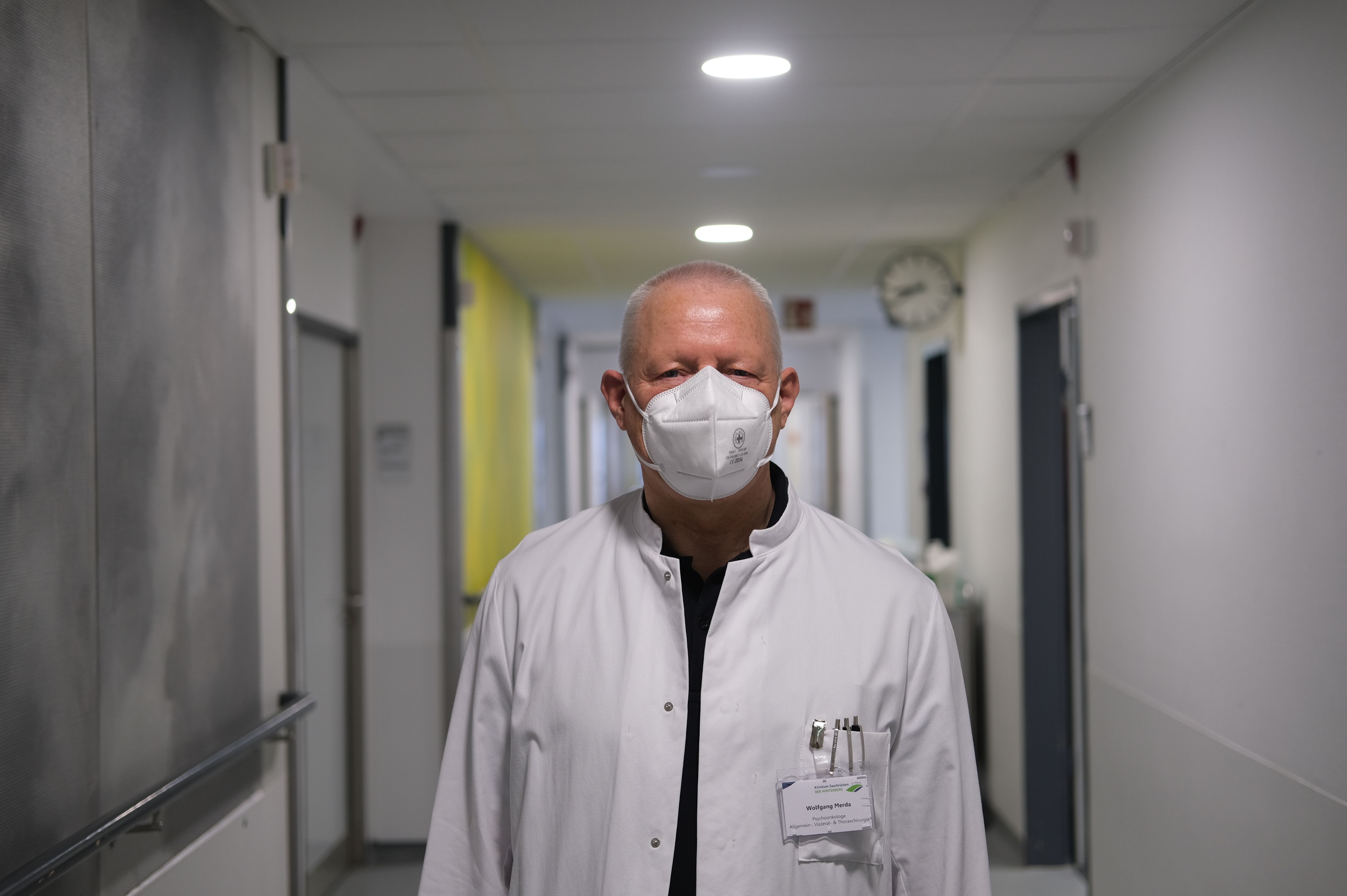 Wolfgang Merda steht in einem Klinik-Flur und schaut in die Kamera
