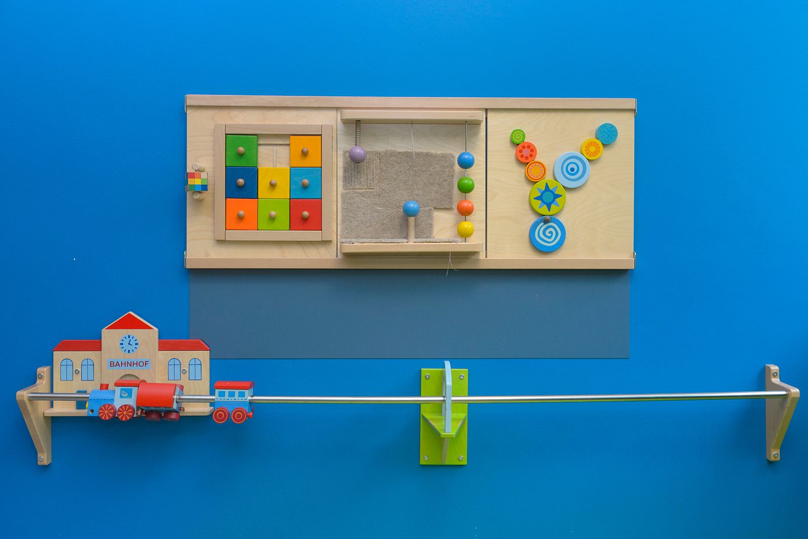 Holzspielzeug befestigt an einer blauen Wand im Spielzimmer in der Kinderklinik