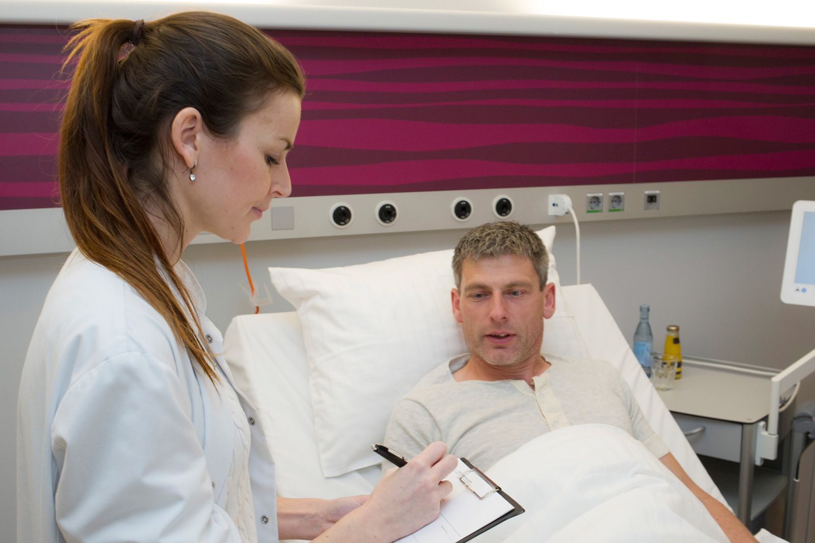 Ärztin macht sich im Gespräch mit Patienten im Zimmer Notizen