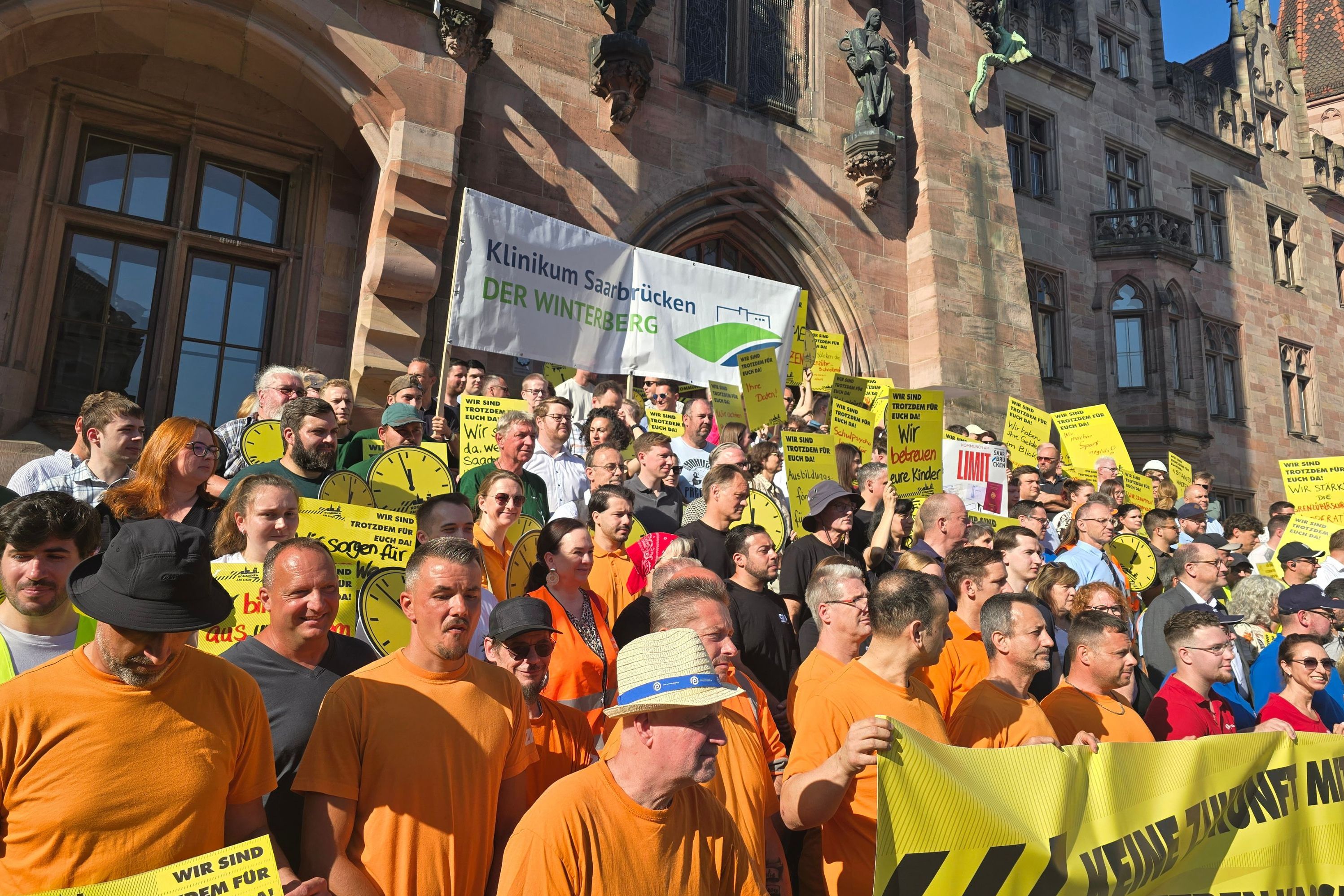 Eine Demonstrantengruppe und in der Mitte eine Gruppe, die ein großes Schild mit "Klinikum Saarbrücken" hoch hält.