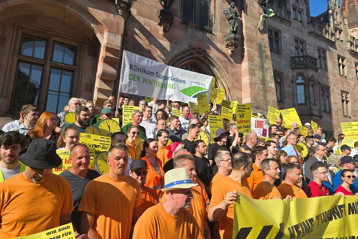 Eine Demonstrantengruppe und in der Mitte eine Gruppe, die ein großes Schild mit "Klinikum Saarbrücken" hoch hält.