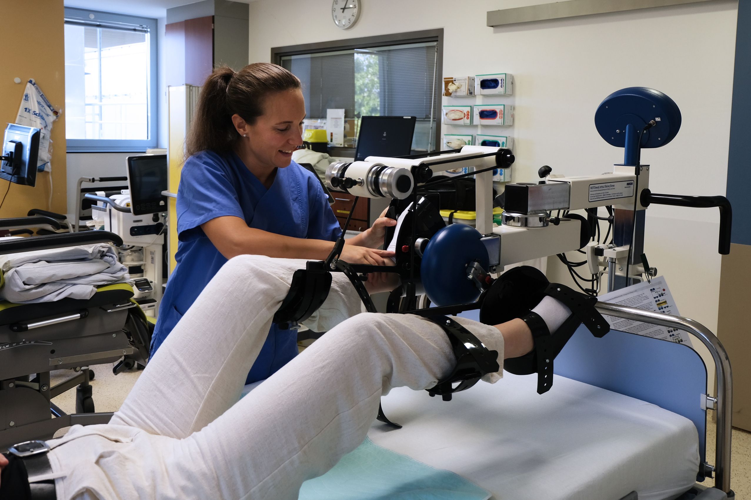 Ergotherapeutin Maike Schmelzer "schnallt" eine Patientin im Bettenfahrrad an zur Mobilisation der Patientin im Bett