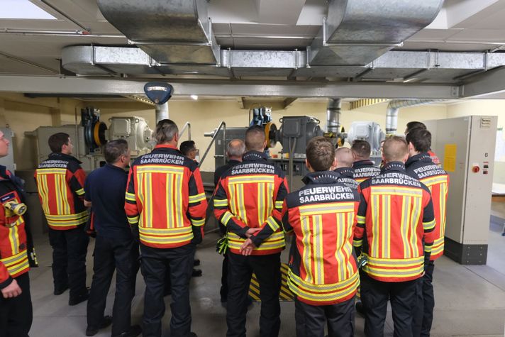 Feuerwehrleute hören zu, was Elektroinstallateur Thomas Bies über die Aufzugssteuerung erklärt.