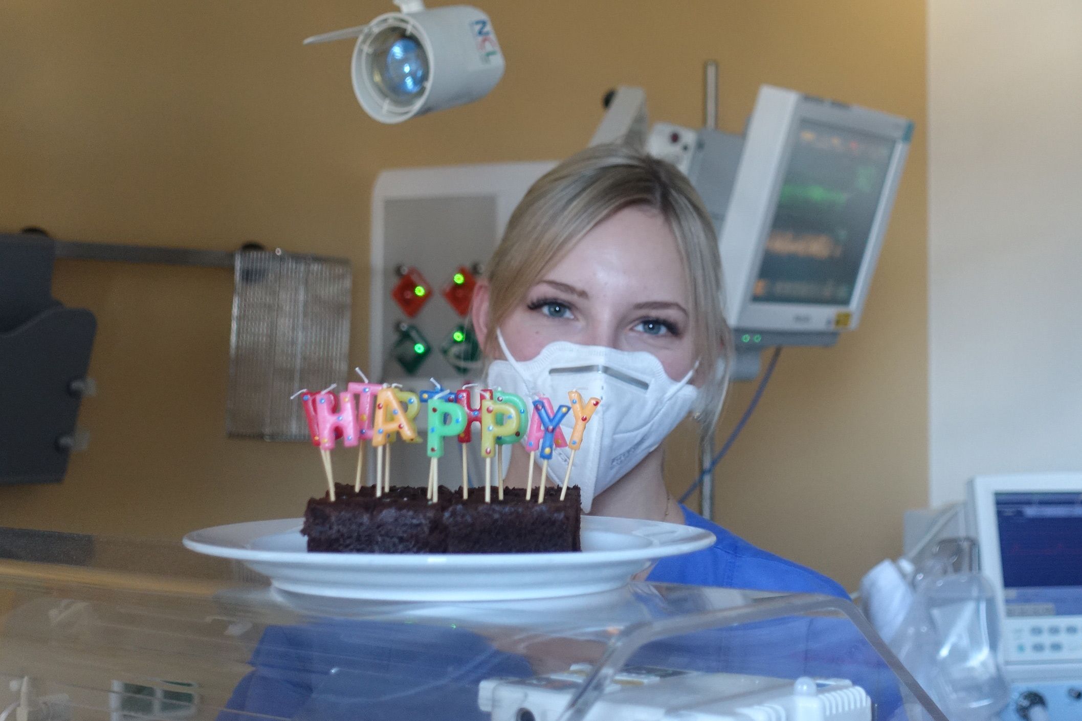 Gesundheits- und Kinderkrankenschwester Agnes Pacek hinter einem Inkubator stehend mit einem "Happy Birthday Geburtstagskuchen"