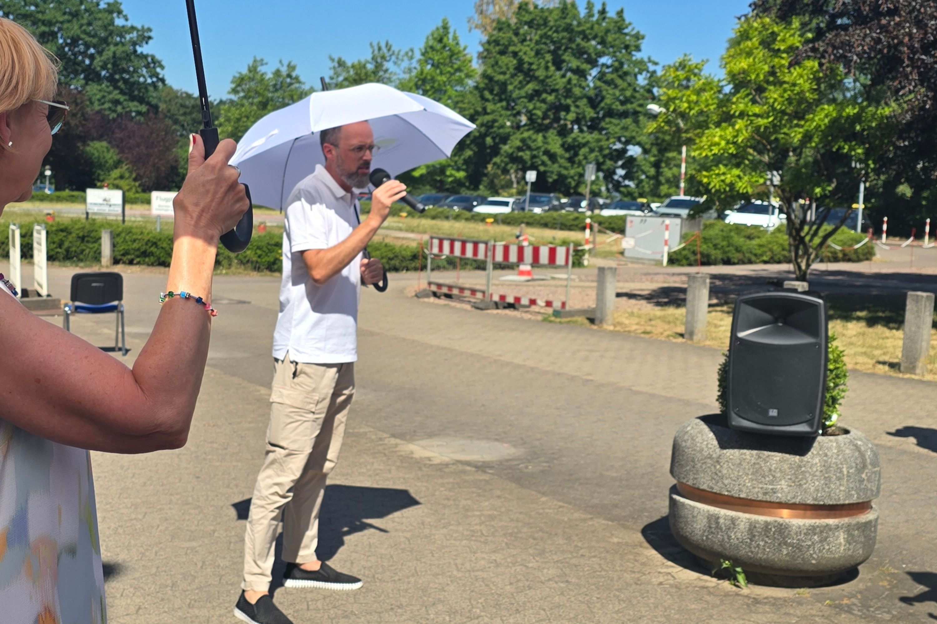 Dr. Christian Braun steht mit Schutzschirm vor dem Haupteingang.