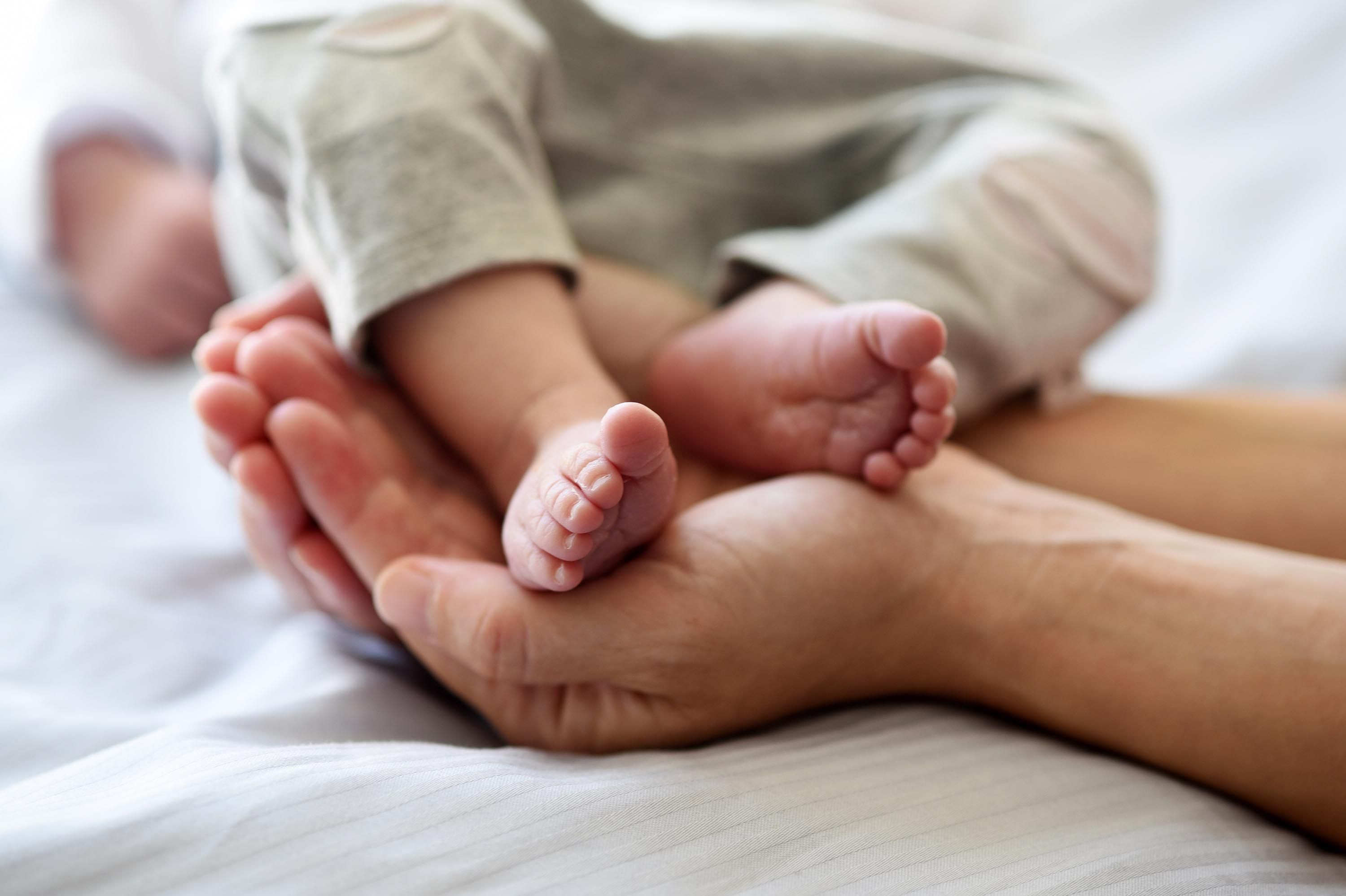 Hände der Eltern halten Babyfüße in einem Krankenhausbett im Klinikum Saarbrücken