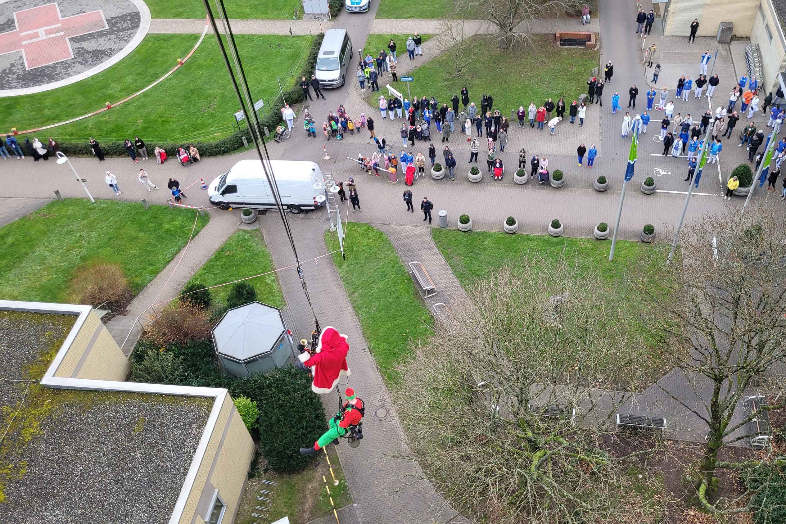 Von oben fotografiert: Der Weihnachtsmann seilt sich vom 9. Stockwerk aus ab. Unten warten Kinder und Erwachsene. 