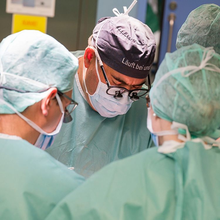 Operationsteam der Allgemeinchirurgie in steriler OP-Kleidung und Fachbrillen bei einem Eingriff im Operationssaal