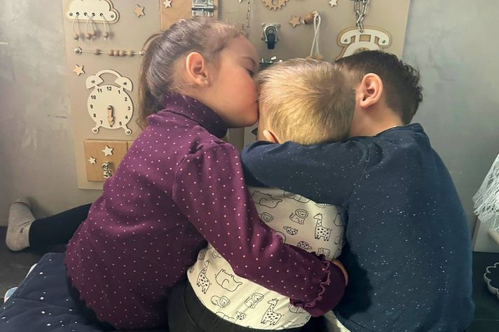 Drei Kinder, die sich umarmen rückseitig