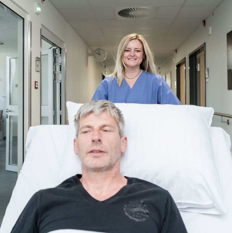 Pflegefachkraft im Klinikum Saarbrücken schiebt ein Bett mit einem Patienten über den Flur