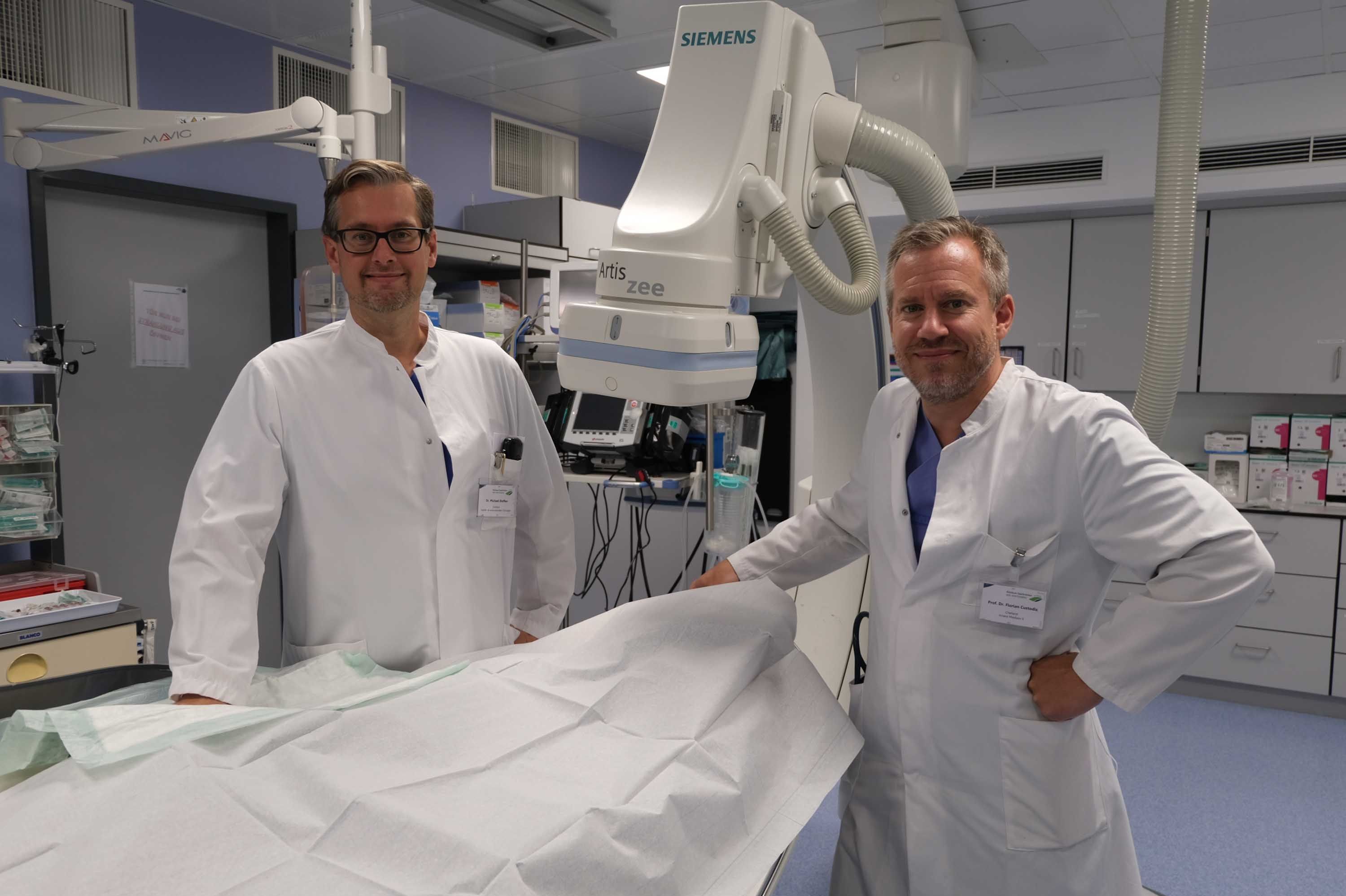 Dr. Steffen und Dr. Custodis stehen in einem Raum, in dem Herzkatheteruntersuchungen durchgeführt werden.