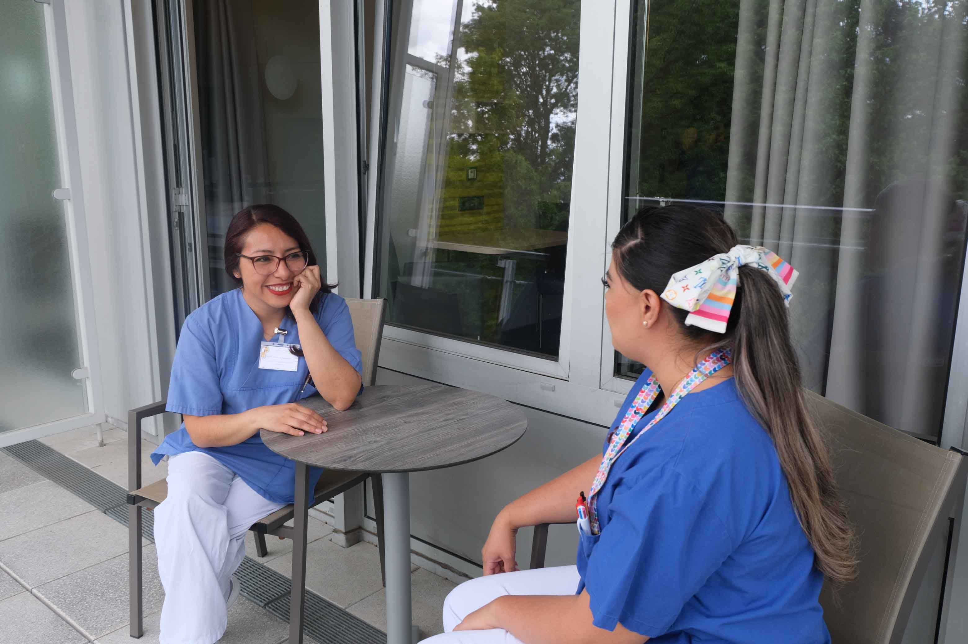 Internationale Fachkräfte im Klinikum Saarbrücken: Zwei Pflegekräfte unterhalten sich in der Pause auf dem Balkon sitzend