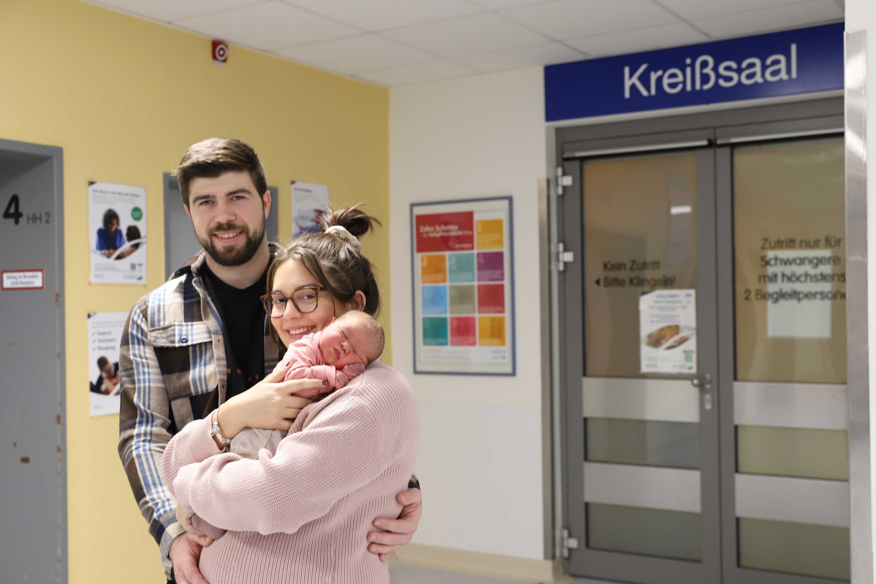 Laura Molon und Julian Dörrschuck halten ihre Tochter Aurora vor dem Kreißsaal in den Armen