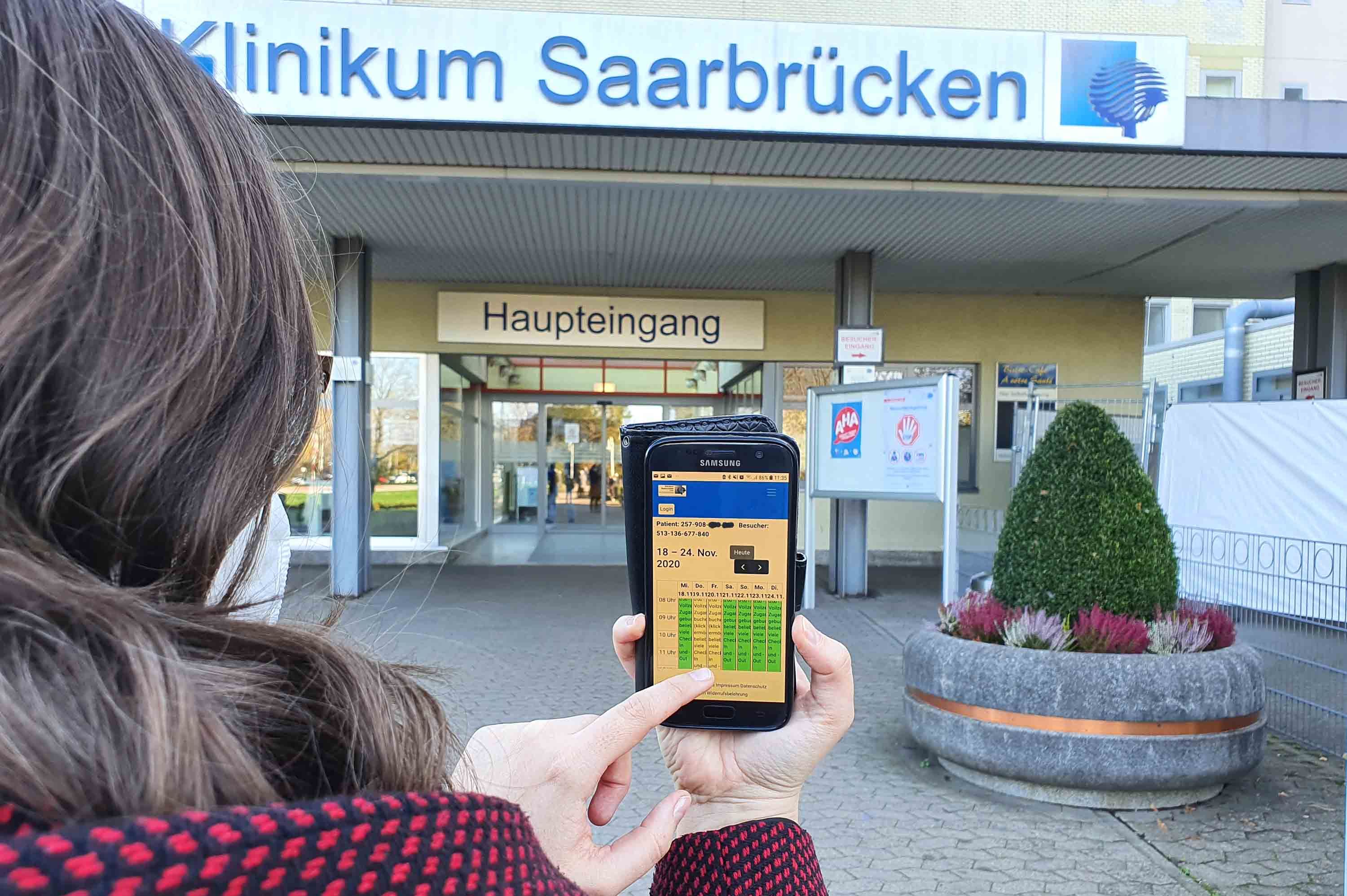 Frau schließt Besucherregistrierung vor dem Klinikum Saarbrücken ab