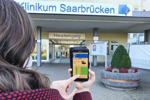 Besucher registriert sich mit dem Handy vorm Klinikum Saarbrücken für Besuch