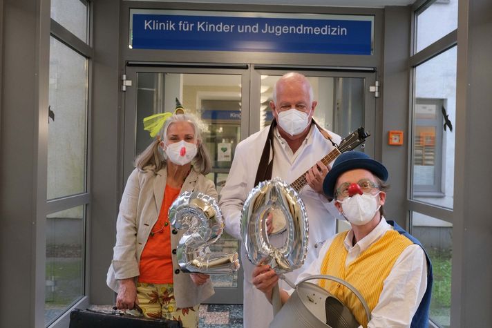 Zwei der Klinikclowns gemeinsam mit dem Chefarzt der Kinderklinik Prof. Dr. Jens Möller vor der Kinderklinik des Klinikums Saarbrücken