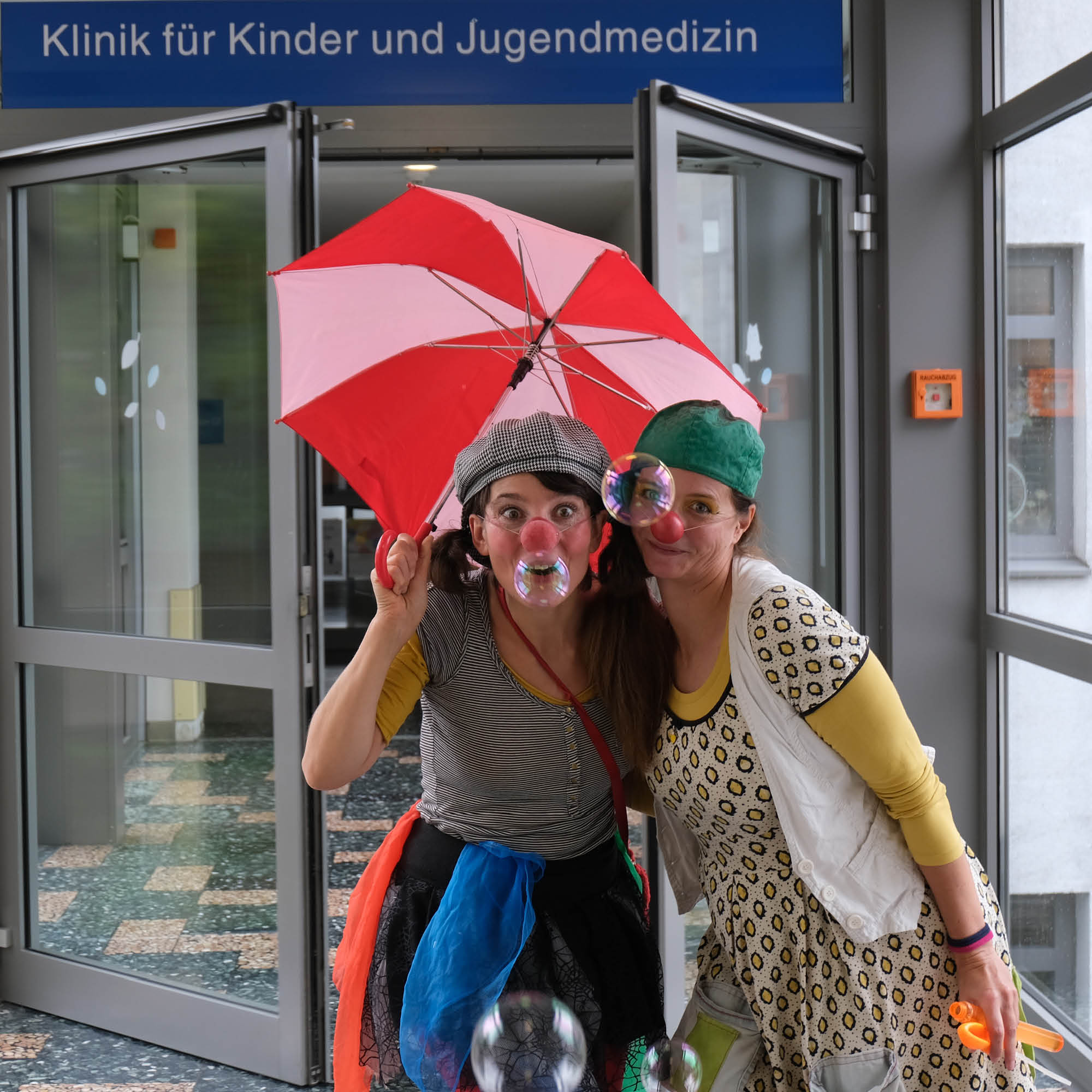 Die Klinik-Clowninnen Mirzel und Lemonella mit Seifenblasen und Verkleidung vor der Klinik für Kinder- und Jugendmedizin im Klinikum Saarbrücken auf dem Winterberg